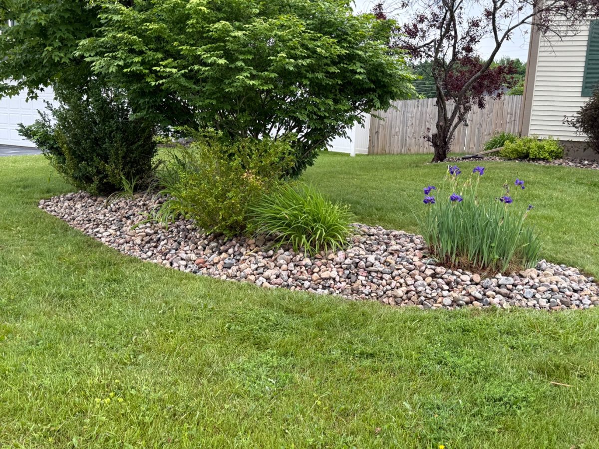 Landscaped garden bed with river rock border by T&R Land Pros
